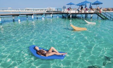 Baigneuse allongée sur un matelas flottant dans l'eau turquoise de Bianca Island